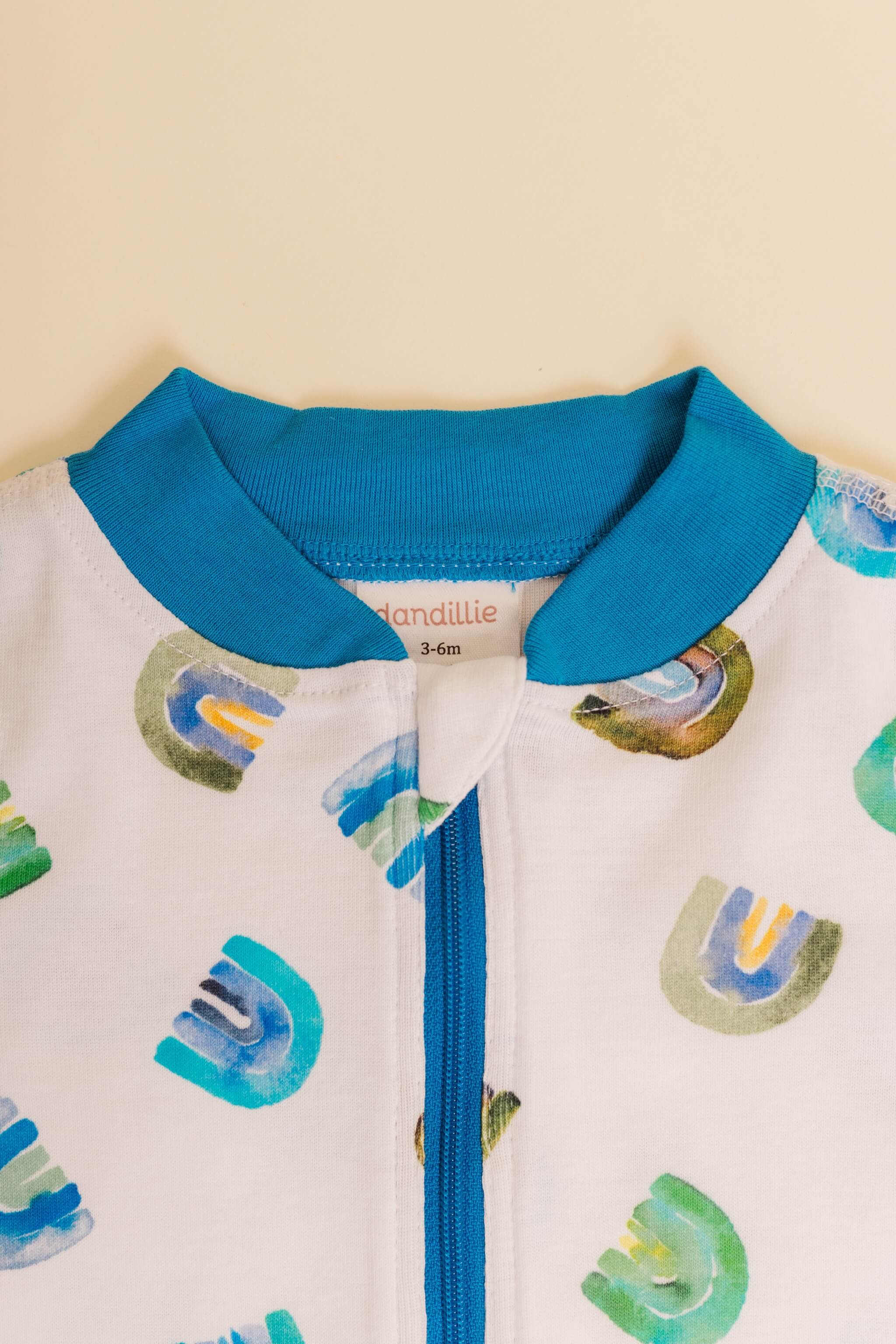 organic cotton baby zipper sleeper with fold-over cuffs in blue rainbow print designed by madeline kerrii