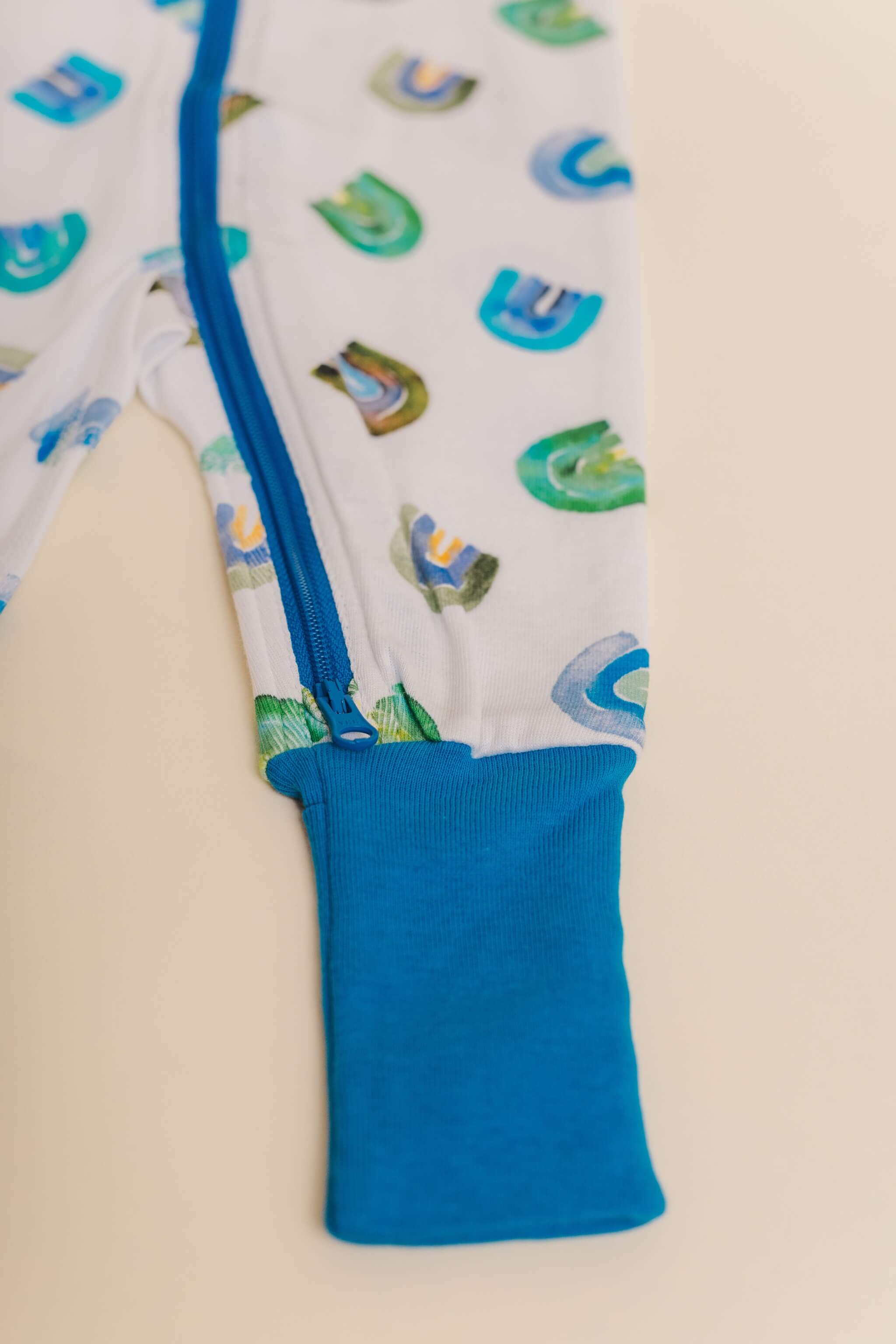organic cotton baby zipper sleeper with fold-over cuffs in blue rainbow print designed by madeline kerrii