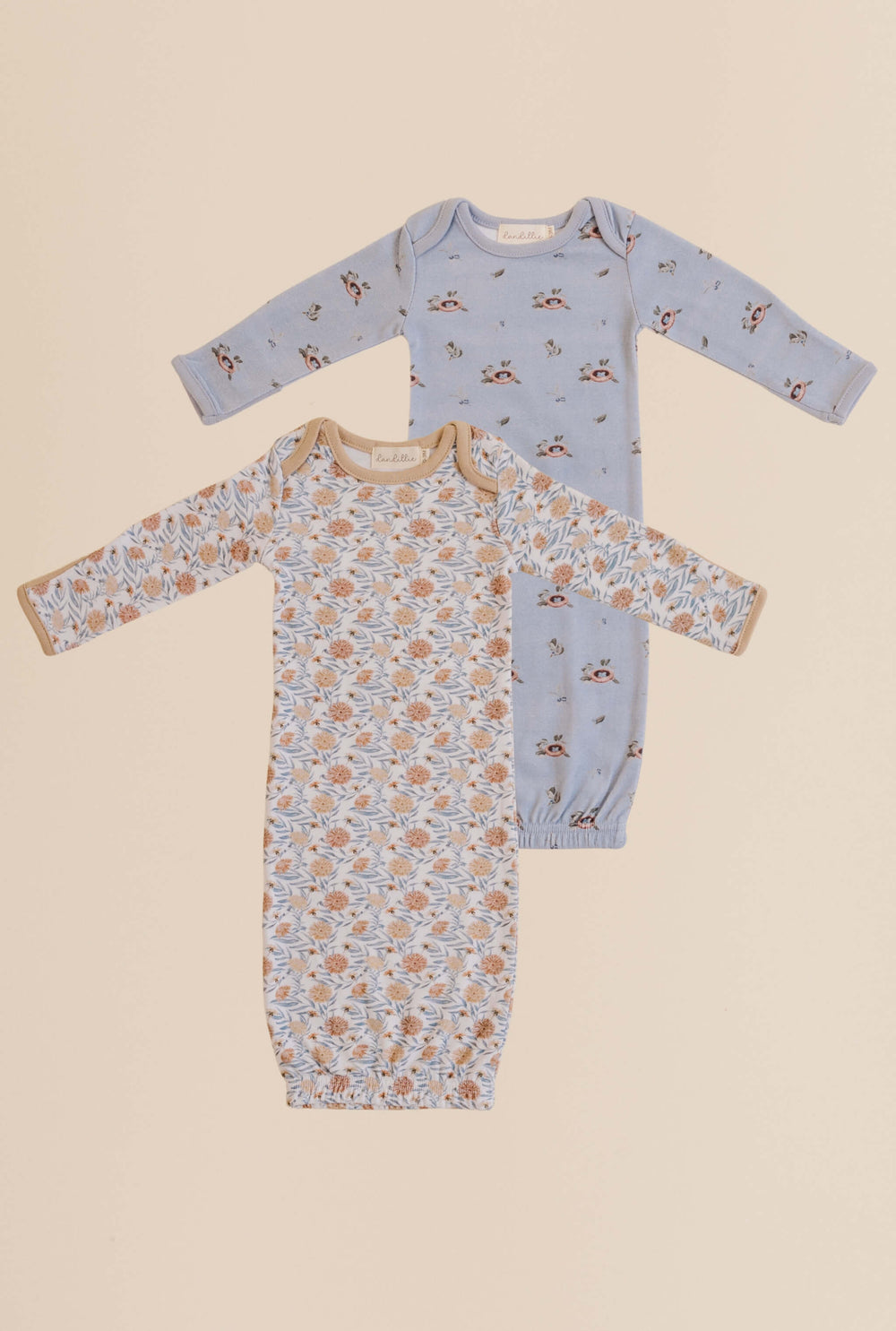 Two baby onesies with floral and bird prints on a beige background