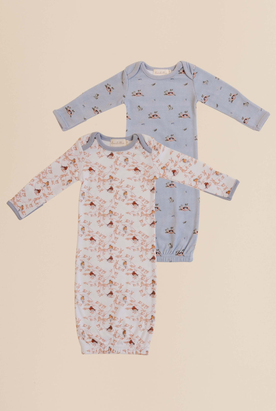 Two baby gowns with bird patterns on a beige and blue background