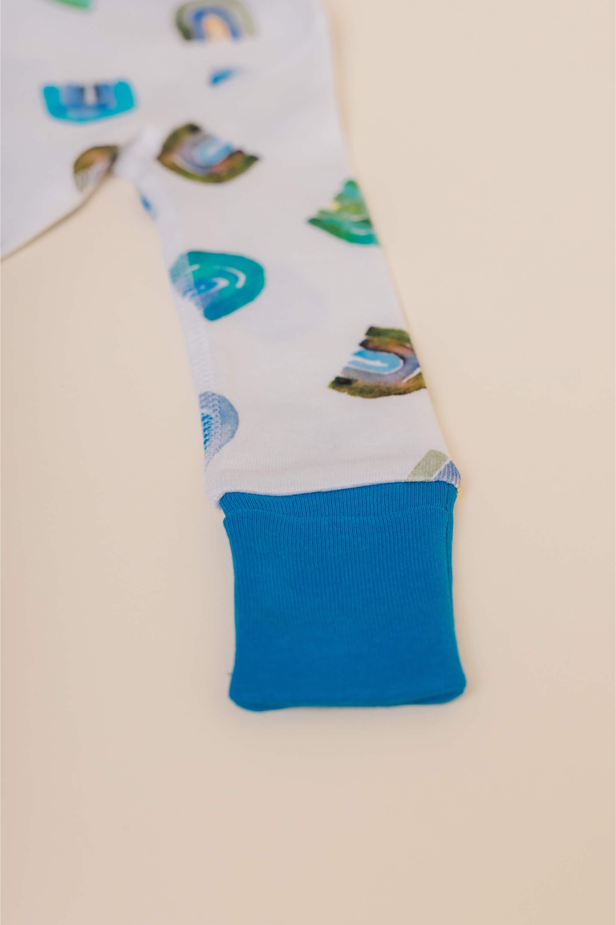 organic cotton baby zipper sleeper with fold-over cuffs in blue rainbow print designed by madeline kerrii